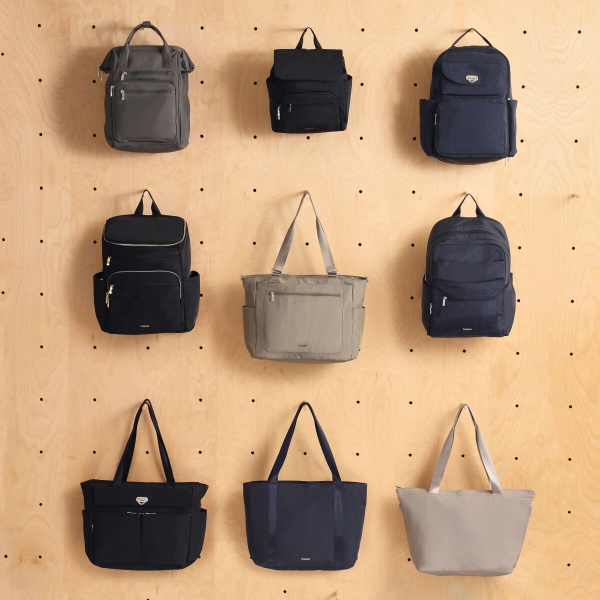 Assortment of Baggallini backpacks and totes displayed on a wood pegboard wall.